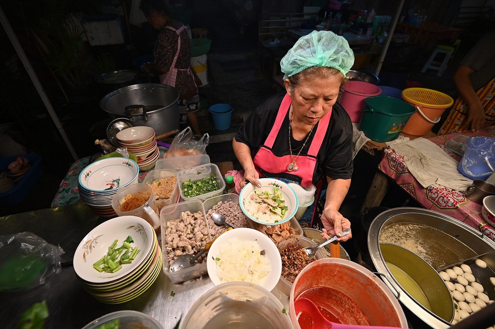 A Thai street-food vendor preparing a bowl of noodles